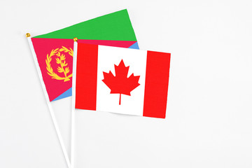 Canada and Eritrea stick flags on white background. High quality fabric, miniature national flag. Peaceful global concept.White floor for copy space.