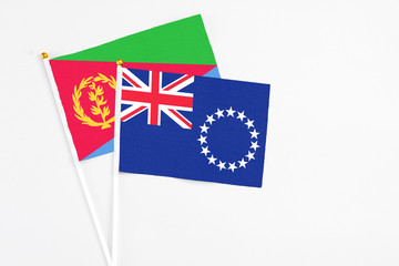 Fototapeta premium Cook Islands and Eritrea stick flags on white background. High quality fabric, miniature national flag. Peaceful global concept.White floor for copy space.