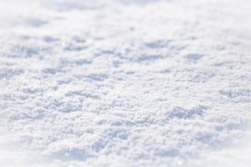 Background of sparkling fresh white snow texture with light blue sky reflection tone.