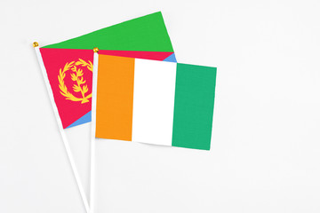 Cote D'Ivoire and Eritrea stick flags on white background. High quality fabric, miniature national flag. Peaceful global concept.White floor for copy space.