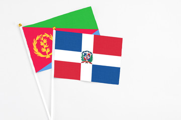Dominican Republic and Eritrea stick flags on white background. High quality fabric, miniature national flag. Peaceful global concept.White floor for copy space.