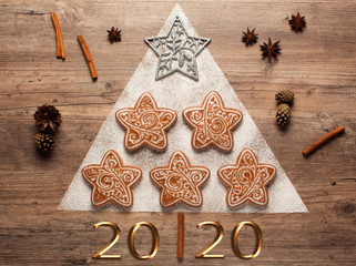 Christmas cookies and cookie cutters on wooden background. Christmas composition. Winter, new year concept. Flat lay, top view. Cones, cinnamon and coriander. 2020