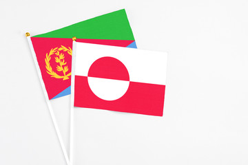 Greenland and Eritrea stick flags on white background. High quality fabric, miniature national flag. Peaceful global concept.White floor for copy space.
