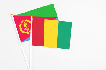 Guinea and Eritrea stick flags on white background. High quality fabric, miniature national flag. Peaceful global concept.White floor for copy space.