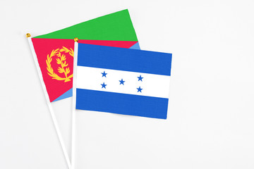 Honduras and Eritrea stick flags on white background. High quality fabric, miniature national flag. Peaceful global concept.White floor for copy space.