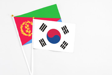 South Korea and Eritrea stick flags on white background. High quality fabric, miniature national flag. Peaceful global concept.White floor for copy space.