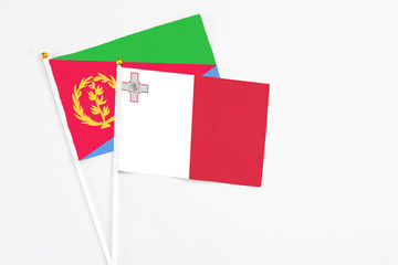 Malta and Eritrea stick flags on white background. High quality fabric, miniature national flag. Peaceful global concept.White floor for copy space.