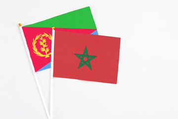 Morocco and Eritrea stick flags on white background. High quality fabric, miniature national flag. Peaceful global concept.White floor for copy space.