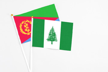 Norfolk Island and Eritrea stick flags on white background. High quality fabric, miniature national flag. Peaceful global concept.White floor for copy space.