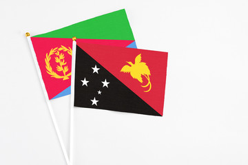 Papua New Guinea and Eritrea stick flags on white background. High quality fabric, miniature national flag. Peaceful global concept.White floor for copy space.
