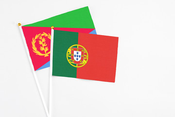 Portugal and Eritrea stick flags on white background. High quality fabric, miniature national flag. Peaceful global concept.White floor for copy space.