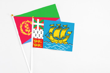 Saint Pierre And Miquelon and Eritrea stick flags on white background. High quality fabric, miniature national flag. Peaceful global concept.White floor for copy space.
