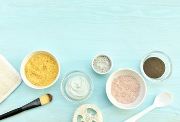 Pink, green, yellow and black cosmetic clay in bowls, natural skin care, flat lay with copy space.
