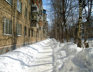 Road cleared from snow. Apartment house.