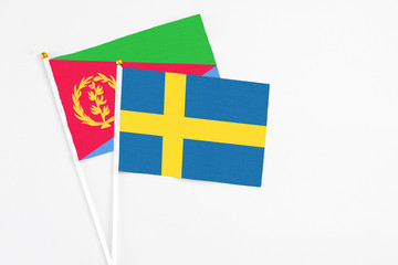 Sweden and Eritrea stick flags on white background. High quality fabric, miniature national flag. Peaceful global concept.White floor for copy space.