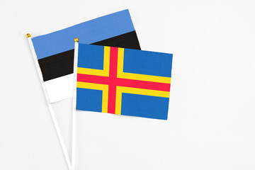 Aland Islands and Estonia stick flags on white background. High quality fabric, miniature national flag. Peaceful global concept.White floor for copy space.