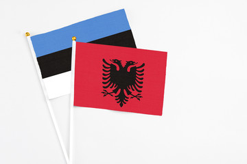 Albania and Estonia stick flags on white background. High quality fabric, miniature national flag. Peaceful global concept.White floor for copy space.
