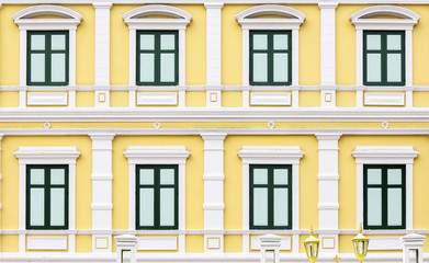 Fototapeta na wymiar Green windows on a yellow building