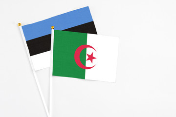 Algeria and Estonia stick flags on white background. High quality fabric, miniature national flag. Peaceful global concept.White floor for copy space.