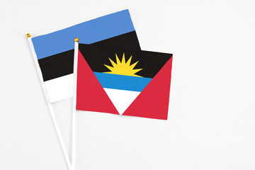Antigua and Barbuda and Estonia stick flags on white background. High quality fabric, miniature national flag. Peaceful global concept.White floor for copy space.