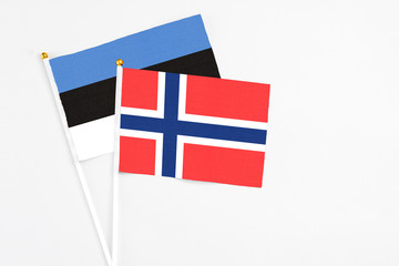 Obraz premium Bouvet Islands and Estonia stick flags on white background. High quality fabric, miniature national flag. Peaceful global concept.White floor for copy space.