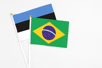 Brazil and Estonia stick flags on white background. High quality fabric, miniature national flag. Peaceful global concept.White floor for copy space.