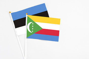 Comoros and Estonia stick flags on white background. High quality fabric, miniature national flag. Peaceful global concept.White floor for copy space.