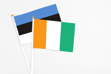 Cote D'Ivoire and Estonia stick flags on white background. High quality fabric, miniature national flag. Peaceful global concept.White floor for copy space.