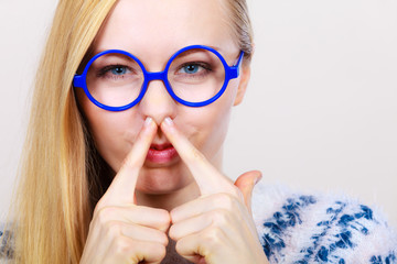 Nerdy woman holding nose smelling bad scent