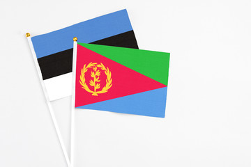 Eritrea and Estonia stick flags on white background. High quality fabric, miniature national flag. Peaceful global concept.White floor for copy space.