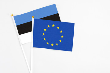 European Union and Estonia stick flags on white background. High quality fabric, miniature national flag. Peaceful global concept.White floor for copy space.