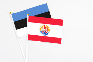 French Polynesia and Estonia stick flags on white background. High quality fabric, miniature national flag. Peaceful global concept.White floor for copy space.