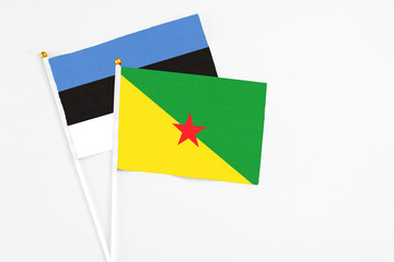 French Guiana and Estonia stick flags on white background. High quality fabric, miniature national flag. Peaceful global concept.White floor for copy space.