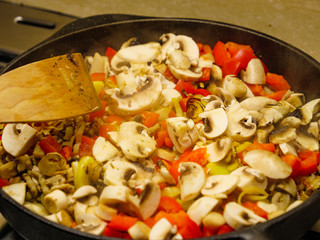 Adding mushrooms to pan vegetables.