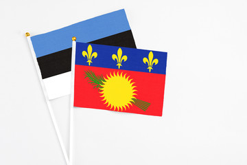 Guadeloupe and Estonia stick flags on white background. High quality fabric, miniature national flag. Peaceful global concept.White floor for copy space.