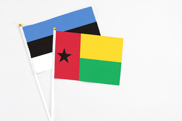 Guinea Bissau and Estonia stick flags on white background. High quality fabric, miniature national flag. Peaceful global concept.White floor for copy space.