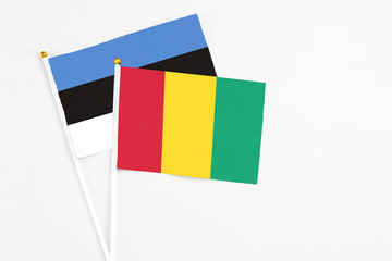 Guinea and Estonia stick flags on white background. High quality fabric, miniature national flag. Peaceful global concept.White floor for copy space.