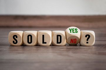 Cubes and dice with sold yes or no on wooden background