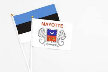 Mayotte and Estonia stick flags on white background. High quality fabric, miniature national flag. Peaceful global concept.White floor for copy space.