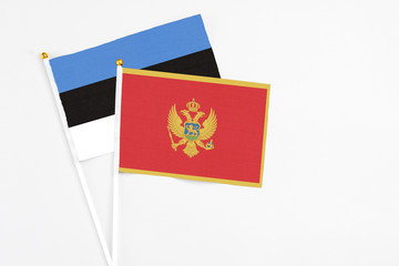 Montenegro and Estonia stick flags on white background. High quality fabric, miniature national flag. Peaceful global concept.White floor for copy space.