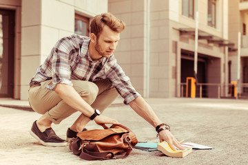 Concentrated young male person taking his book
