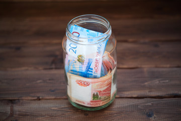 Money in a glass jar on a wooden background