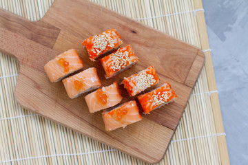 Japanese cuisine. Sushi roll with salmon, leeks, tuna, avocado, king prawn, Philadelphia cream cheese, caviar with tobiko. Sushi menu. The view from the top. rolls on a wooden Board.