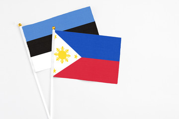 Philippines and Estonia stick flags on white background. High quality fabric, miniature national flag. Peaceful global concept.White floor for copy space.