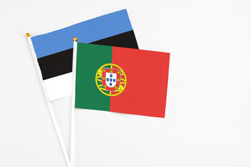 Portugal and Estonia stick flags on white background. High quality fabric, miniature national flag. Peaceful global concept.White floor for copy space.