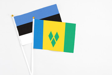 Saint Vincent And The Grenadines and Estonia stick flags on white background. High quality fabric, miniature national flag. Peaceful global concept.White floor for copy space.