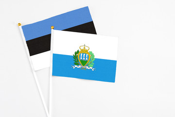 San Marino and Estonia stick flags on white background. High quality fabric, miniature national flag. Peaceful global concept.White floor for copy space.
