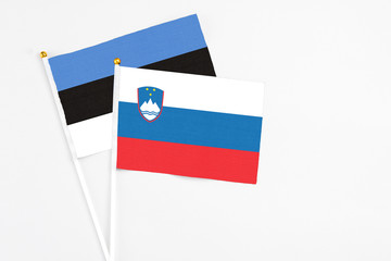 Slovenia and Estonia stick flags on white background. High quality fabric, miniature national flag. Peaceful global concept.White floor for copy space.