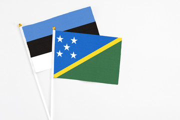 Solomon Islands and Estonia stick flags on white background. High quality fabric, miniature national flag. Peaceful global concept.White floor for copy space.