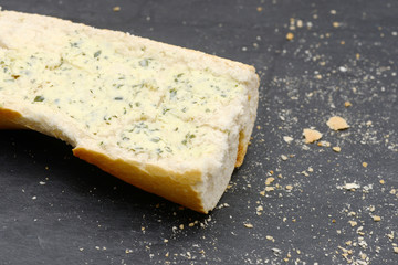 rustic crusty white bread with Herb butter lying on black slate in the kitchen